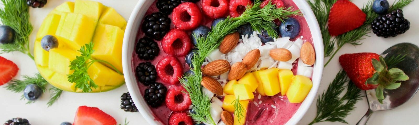 A vibrant, healthy fruit smoothie bowl topped with fresh berries, mango, and almonds.