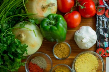 An assortment of fresh vegetables and spices on a wooden table for healthy cooking.