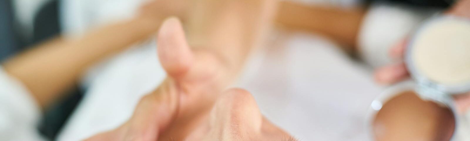 Close-up view of a professional makeup artist applying cosmetics indoors, highlighting beauty and skin care.