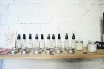 Minimalist skincare products displayed on a wooden shelf against a white brick wall.