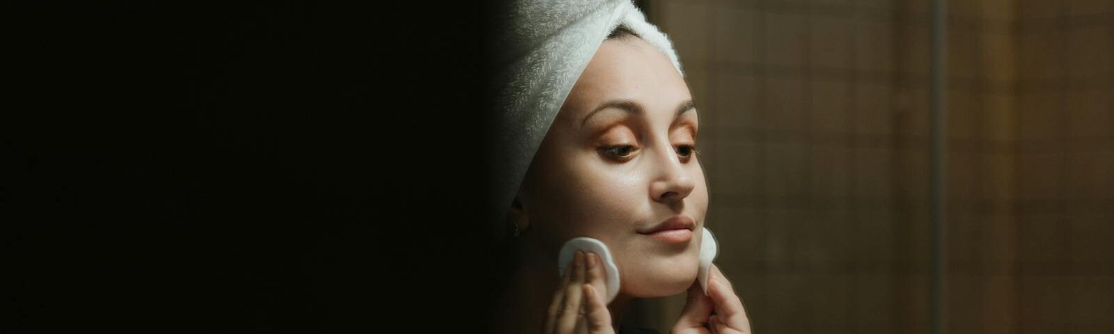 A woman uses cotton pads for face cleansing as part of her self-care routine in the bathroom.