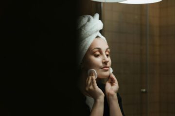 A woman uses cotton pads for face cleansing as part of her self-care routine in the bathroom.