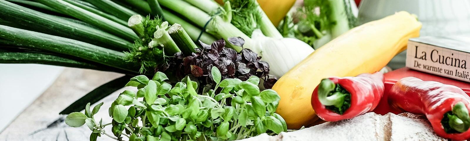 A vibrant assortment of fresh vegetables, herbs, and bread on a rustic surface, ideal for culinary scenes.