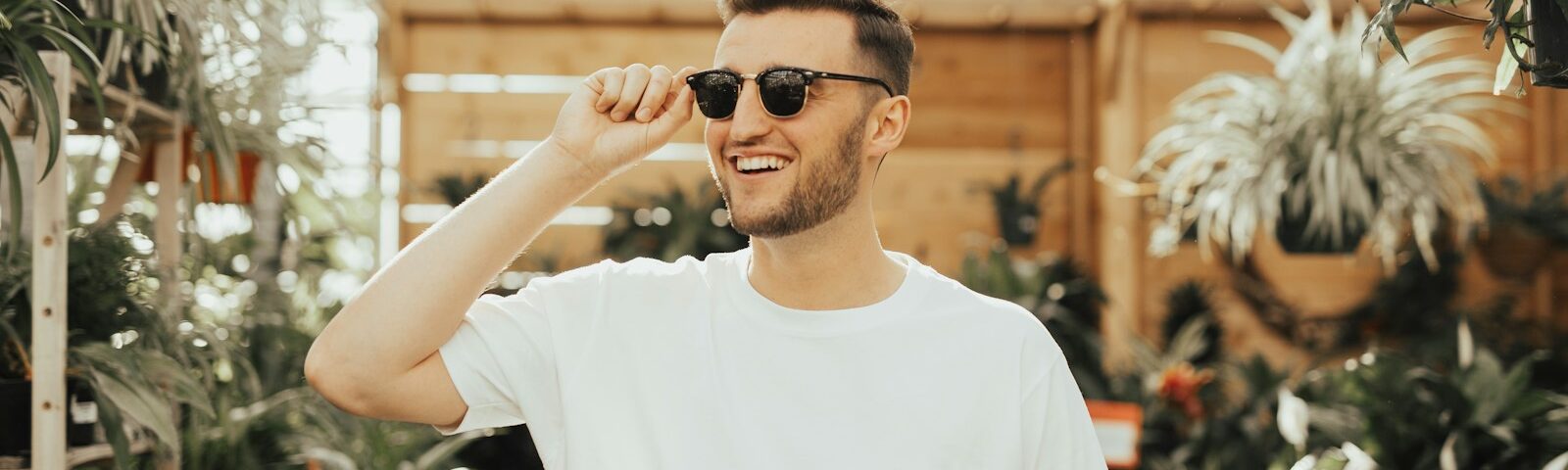 man in white crew-neck shirt wearing sunglasses standing near plants