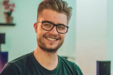 man wearing green crew-neck top and eyeglasses with black frames looking at side